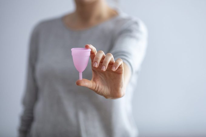 Young woman hand holding menstrual cup.