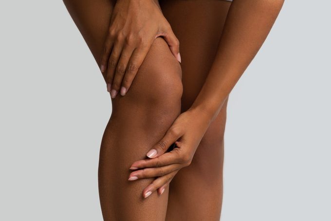 Zwarte vrouw masseert haar pijnlijke knie, close-up