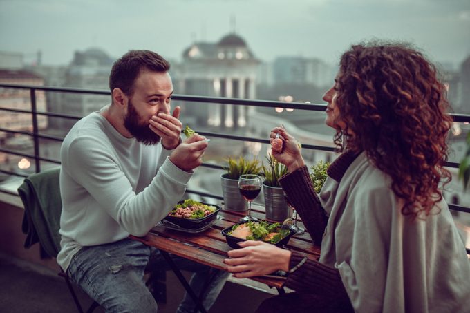 Paar lächelt und genießt das Date mit Mittagessen auf dem Dach des Gebäudes