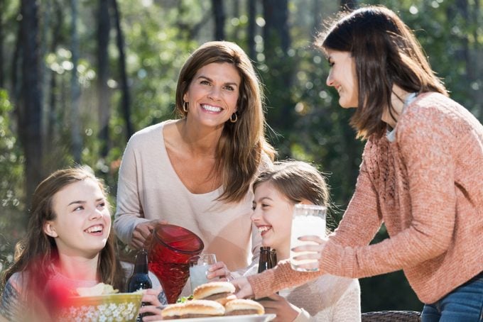 Madre e figlie su un picnic versando limonata
