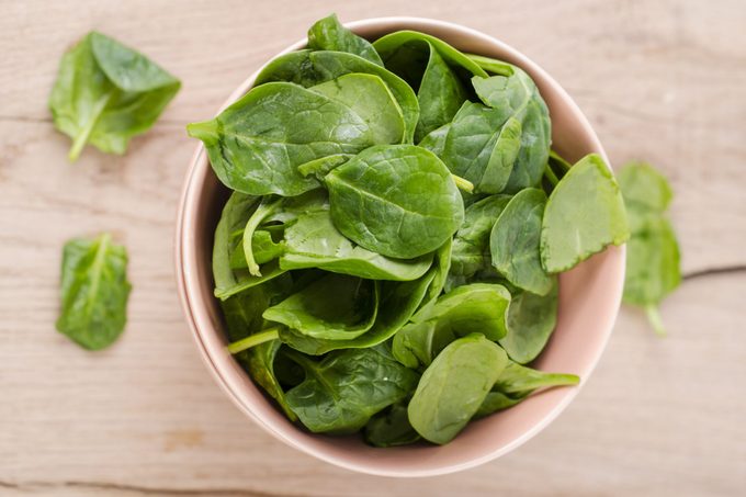 Bowl of fresh spinach leaves on wood