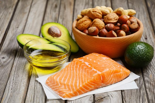 Vitamin D Foods on a wooden background; avocado, olive oil, salmon, and nuts in a bowl