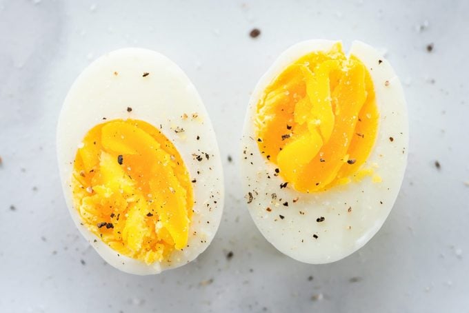 Hard Boiled Egg cut in half with some sprinkled pepper on a marble countertop surface