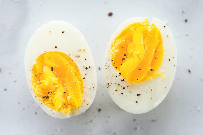 Hardgekookt ei in tweeën gesneden met wat bestrooide peper op een marmeren aanrechtblad