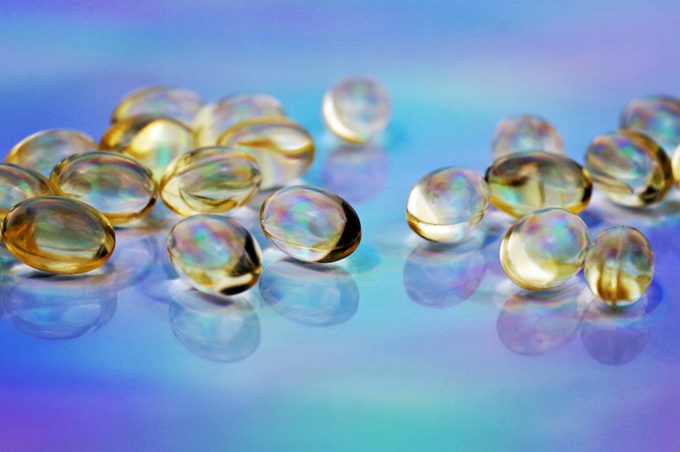 Gel Caps of vitamin d on a holographic foil background