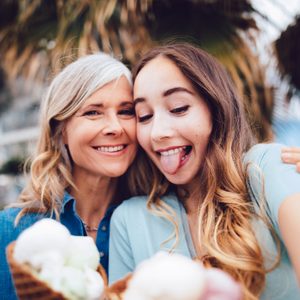 Happy grandmother and adult granddaughter with ice-cream taking selfies outdoors