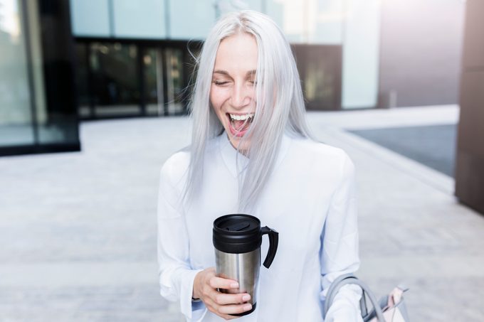 Mujer de negocios joven gritando con taza de café en la ciudad