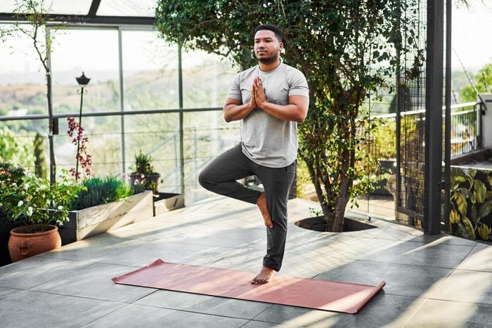 Hombre al aire libre haciendo pose de yoga para fortalecer los huesos, el árbol