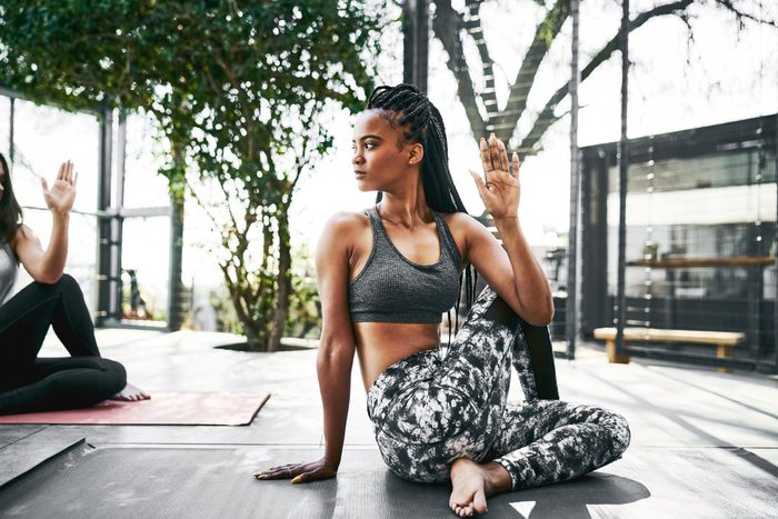 young woman does bone strengthening yoga outside on a yoga mat, bent leg twist pose