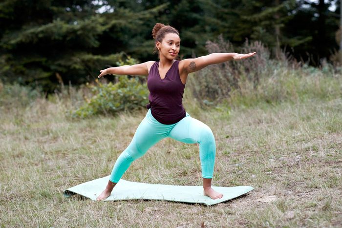 woman outside does warrior 2 yoga pose to strengthen bones