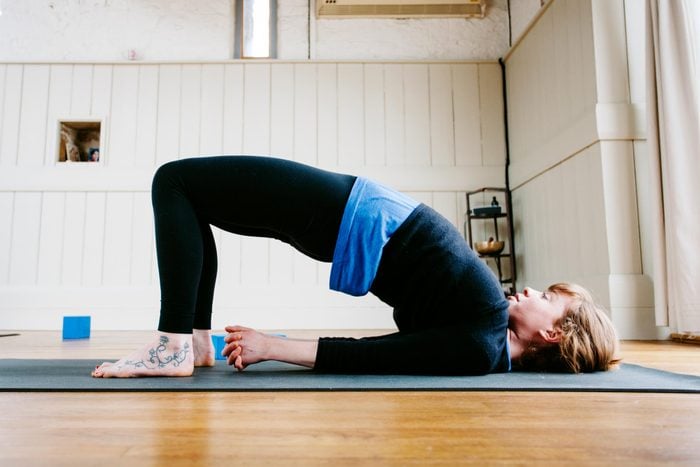 woman does a bridge pose for bone strengthening yoga inside on a yoga mat