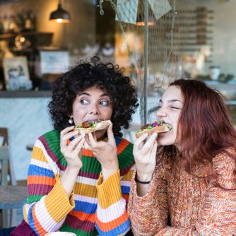 Young woman having breakfast with friend while sitting at restaurant