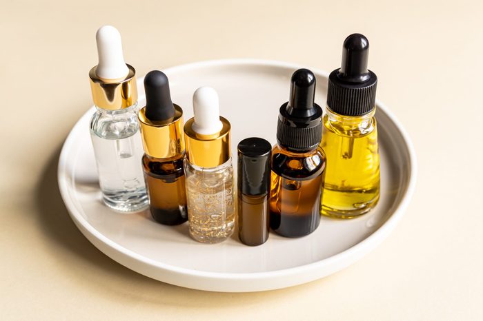 set of different dropper bottles with beauty care serum, hyaluronic acid and vitamins on ceramic tray. Home cosmetics and spa concept