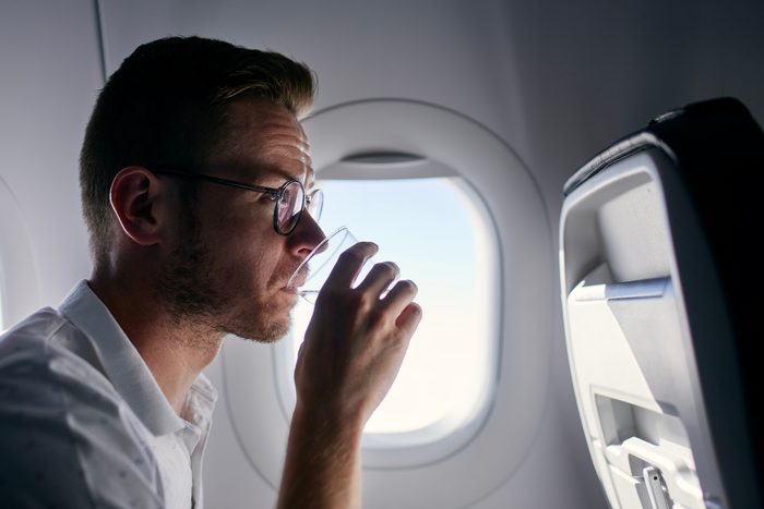 Man drinking water from plastic cup in airplane