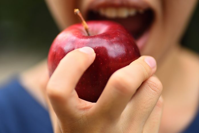 анонимный крупный план человека, поедающего яблоко