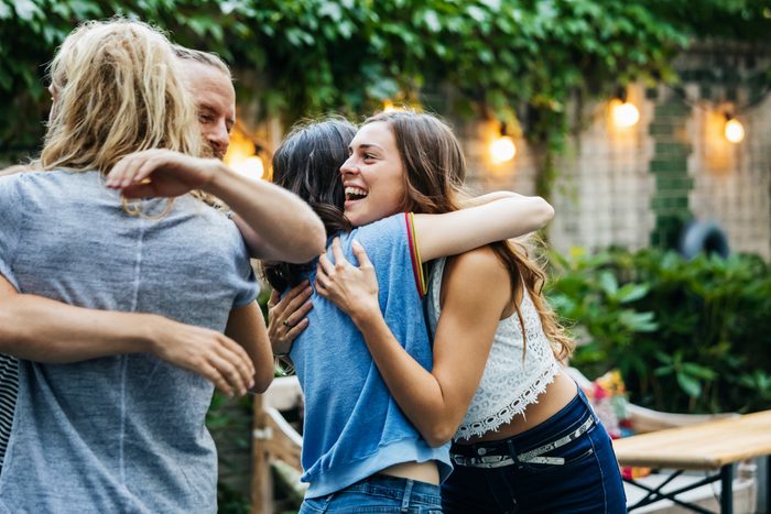 A Group Of Friends Embrace, Excited To See Each Other At Barbecue Meetup