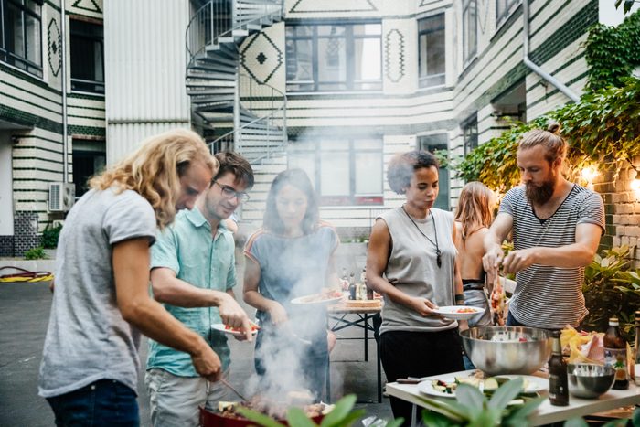 Group Of Friends Gathered At Barbecue Eating And Socialising