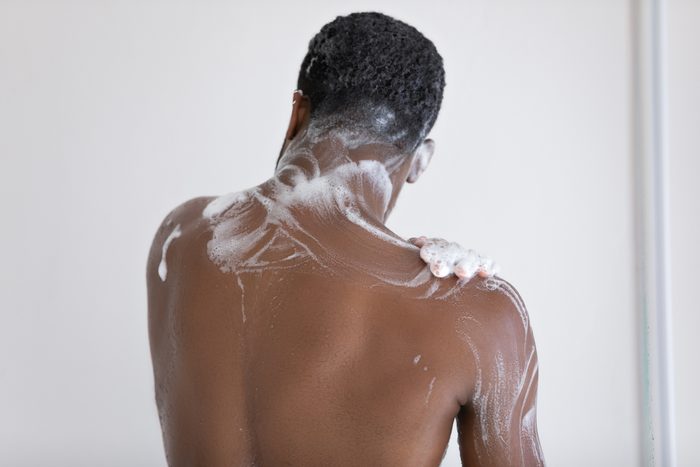 Back view of biracial man wash taking shower