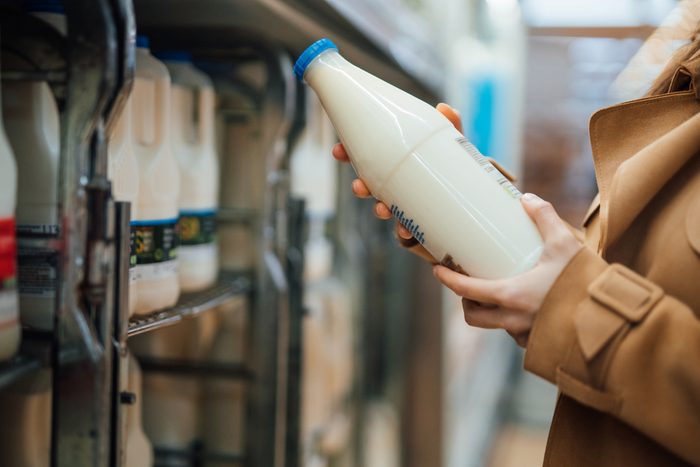 Close up shot of woman holding a bottle of organic fresh milk in supermarket