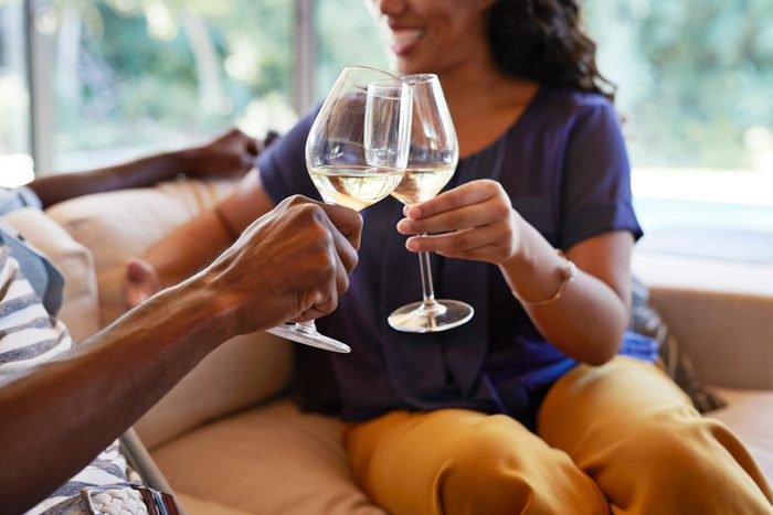 Couple toasting on a couch with glasses of white wine