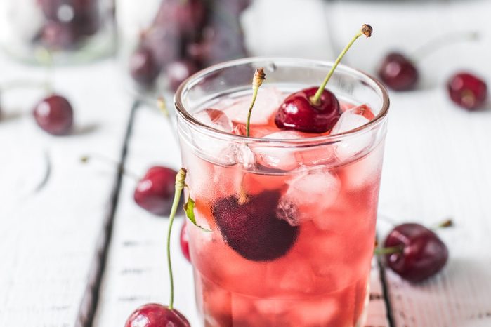 clear glass with iced cherry juice with fresh cherries