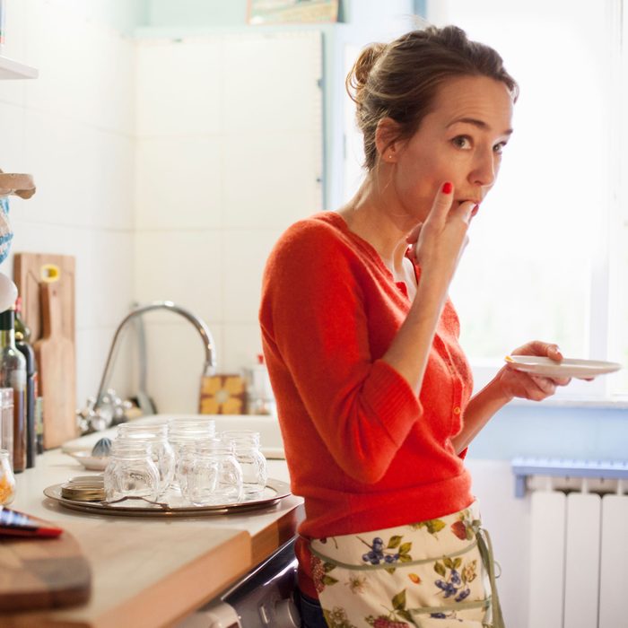 Woman In Kitchen Tasting something on her finger