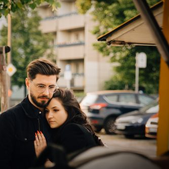 Man embracing sad woman while standing in city