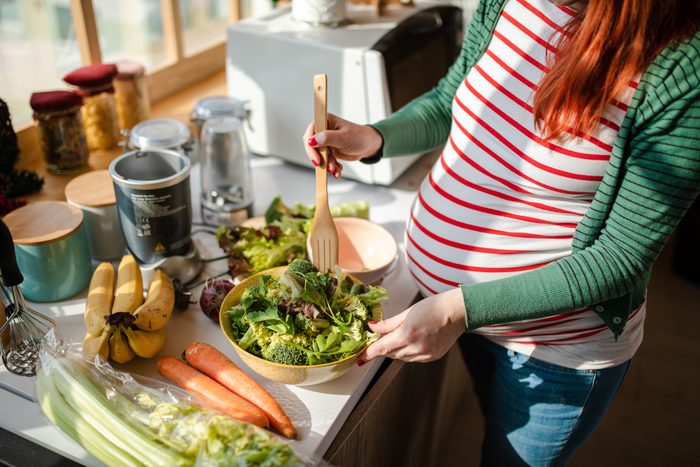 Healthy pregnant woman preapring a fresh organic salad for her breakfast