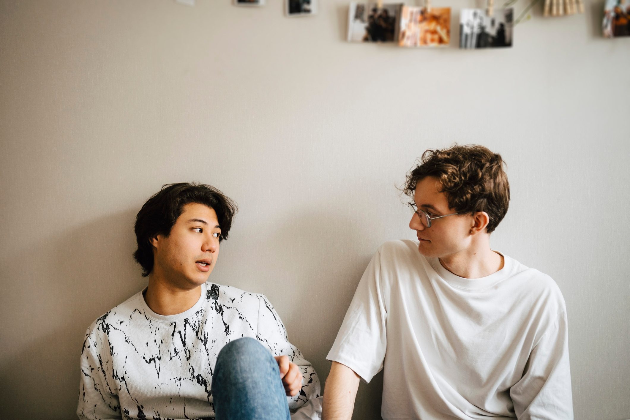 Male couple talking while sitting in bedroom at home