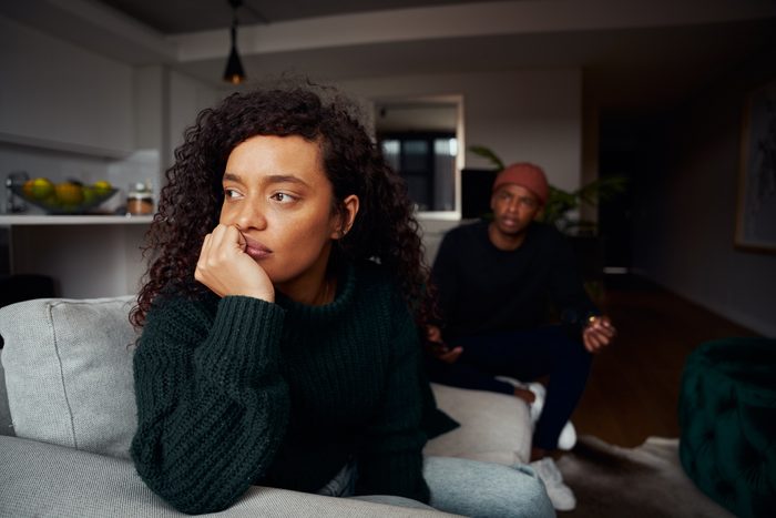 Multi-cultural female ignoring black boyfriend while fighting on the sofa in modern apartment