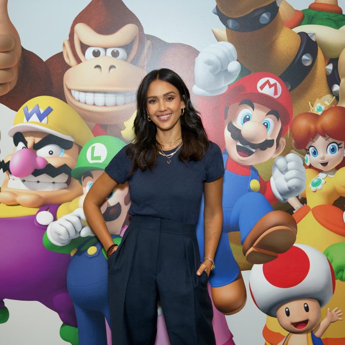 Jessica Alba in front of a wall of Mario characters