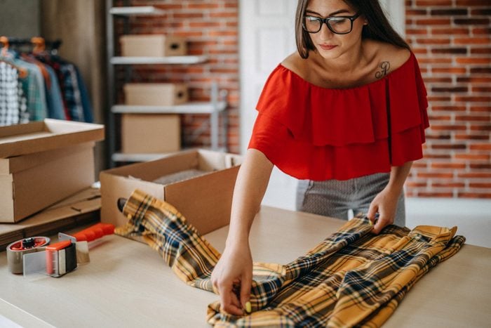 Woman packing yellow flannel shirt that she sold online
