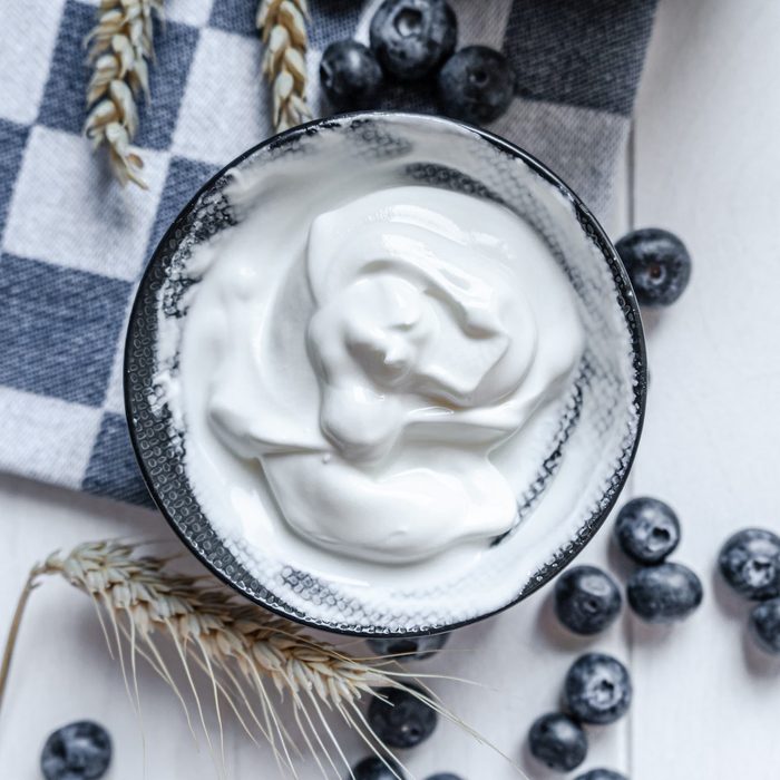 yogurt in bowl on wooden table with blueberries