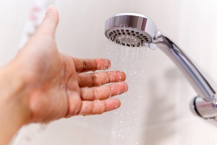 a man's hand under a stream of water in the shower