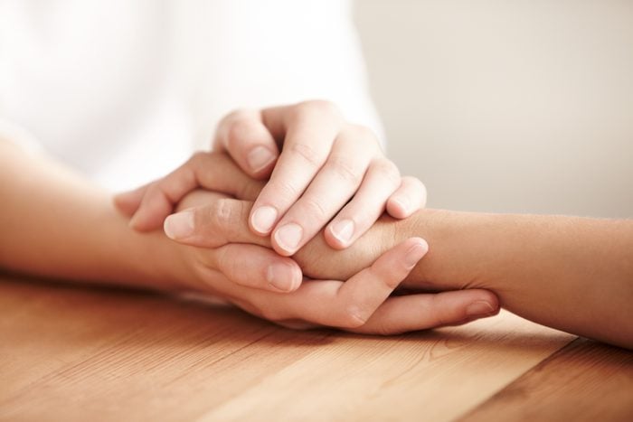 Hands holding one another on a table