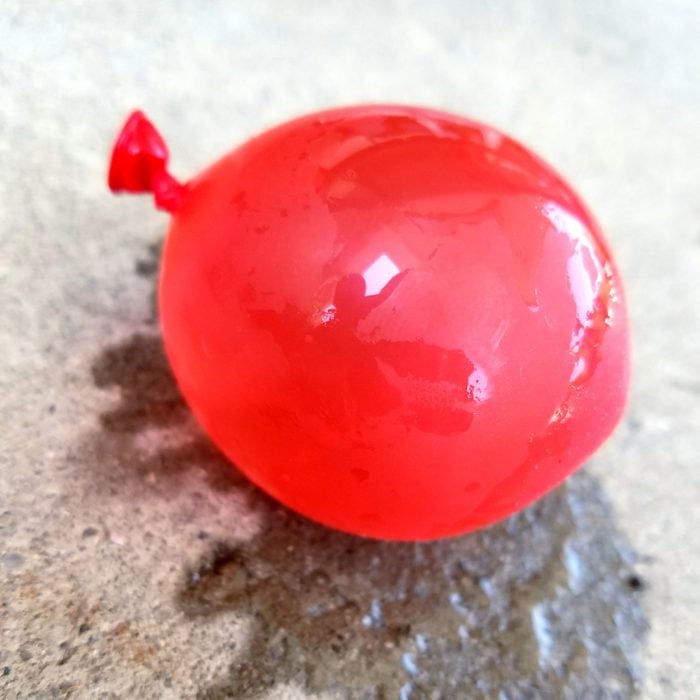 red Balloon Full Of Water with a water mark on the concrete under the balloon