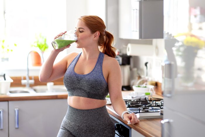 Redhead woman drinking healthy smoothie after working out at home