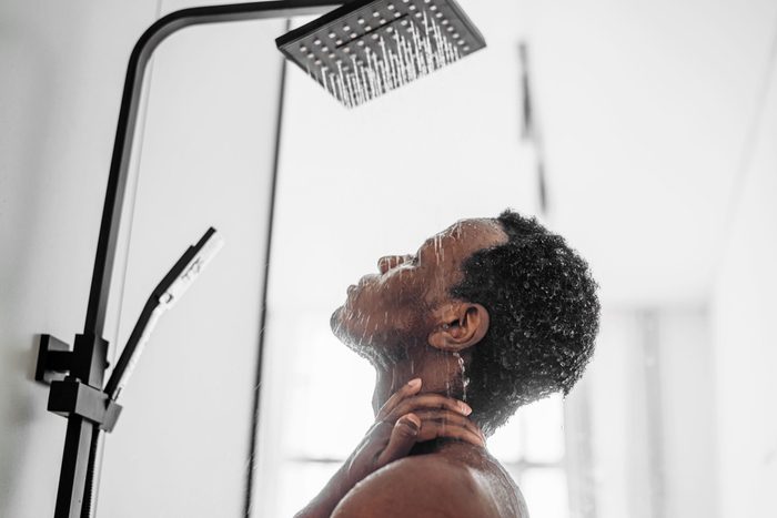 Relaxed African-American man takes shower in bathroom