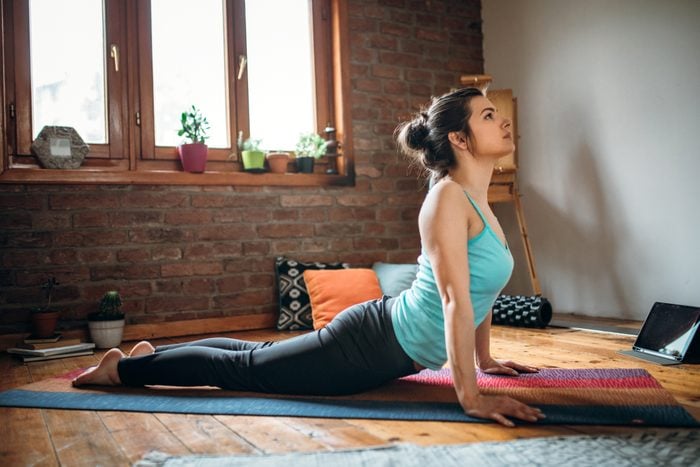 Young yoga instructor stretching in her living room making upward facing dog pose