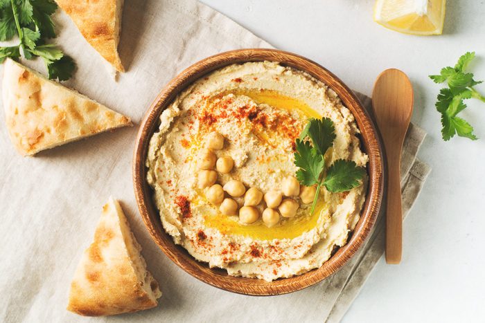 Hummus dip with chickpea, pita and parsley in wooden plate on white background