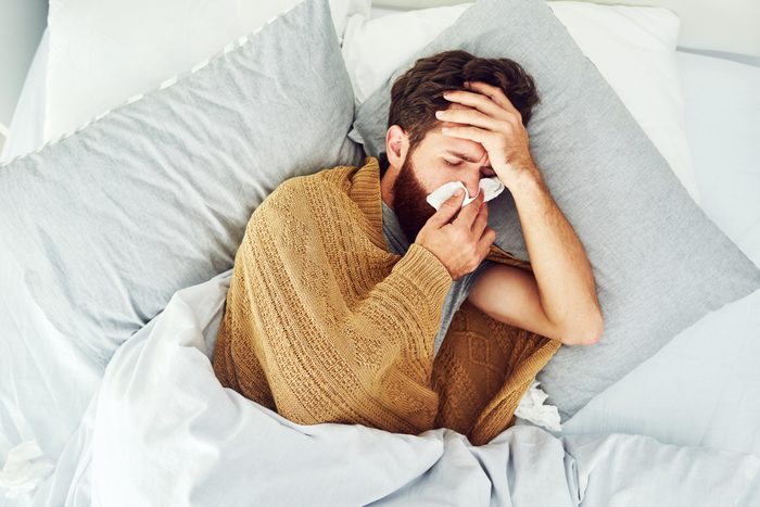 man with allergies using a tissue in bed
