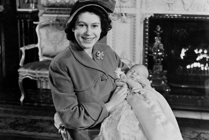 black and white photograph of Queen ELIZABETH II sitting and holding baby Charles
