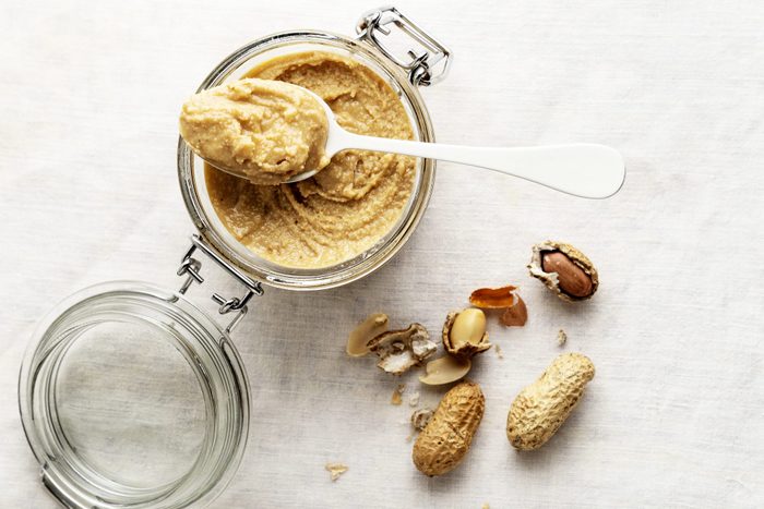 peanut butter I na jar with a spoon and peanuts to the side