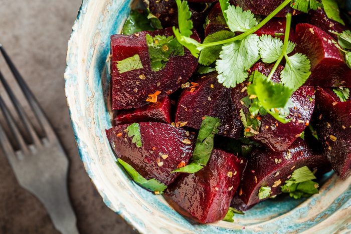 Baked beetroot salad with cilantro in bowl, top view. Healthy vegan food concept.