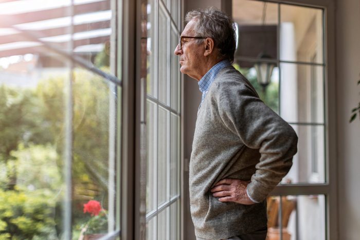 Senior man looking out of window at home