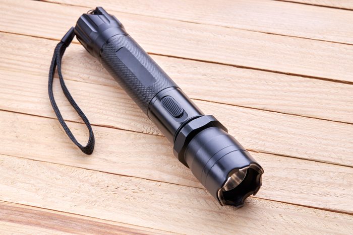 black tactical flashlight on wooden bench background