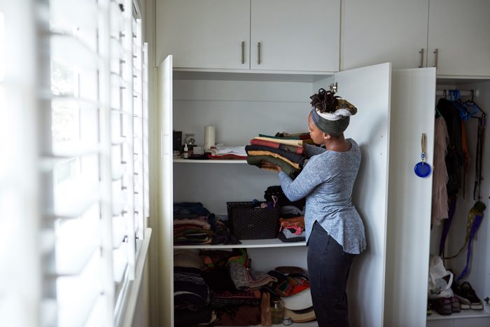 Cropped shot of a young woman packing away clean laundry at home