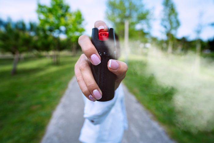 anonymous Woman using pepper spray for self defense outdoors