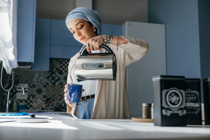 Woman wearing a turquoise turban preparing breakfast at home before leaving to work.