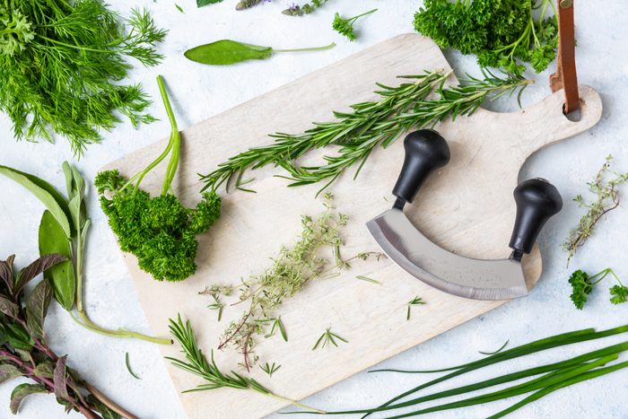Mezzaluna knife with assorted fresh herbs on a chopping board